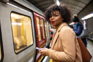 一名女子拿着手机准备在地铁站上火车
